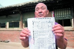 姜先生在自家院内展示从档案馆取出的1950年的土地使用证
